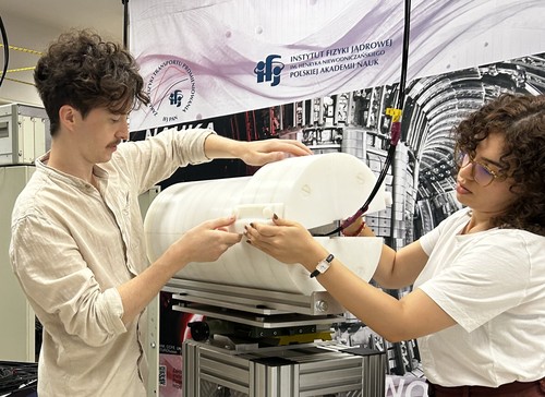 Dwie osoby obsługują maszynę w zamkniętej przestrzeni.