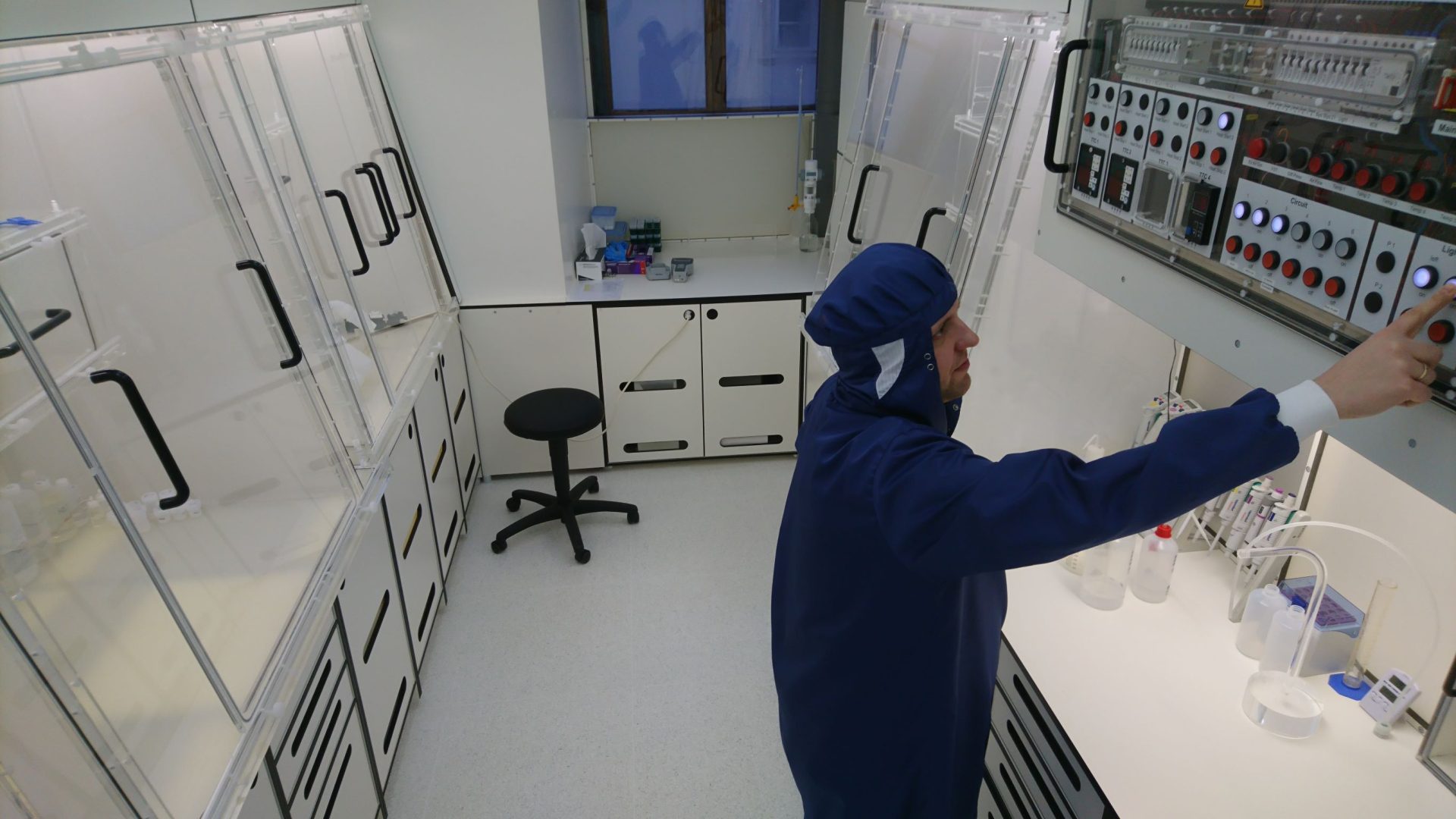 Naukowiec w niebieskim kombinezonie w białym laboratorium