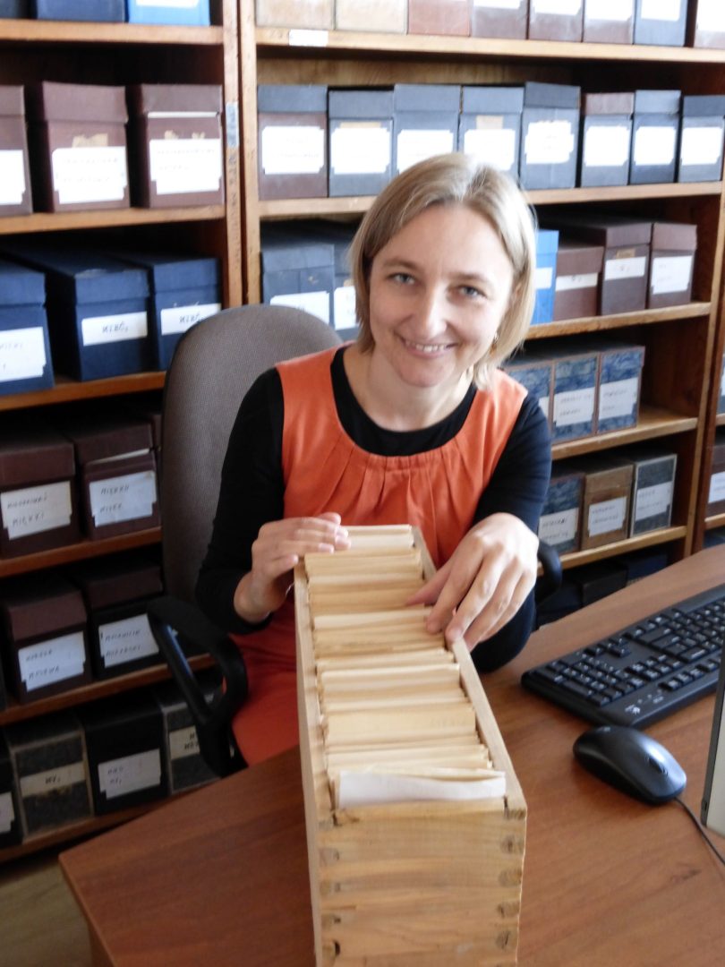 Uśmiechnięta kobieta przegląda fiszki biblioteczne