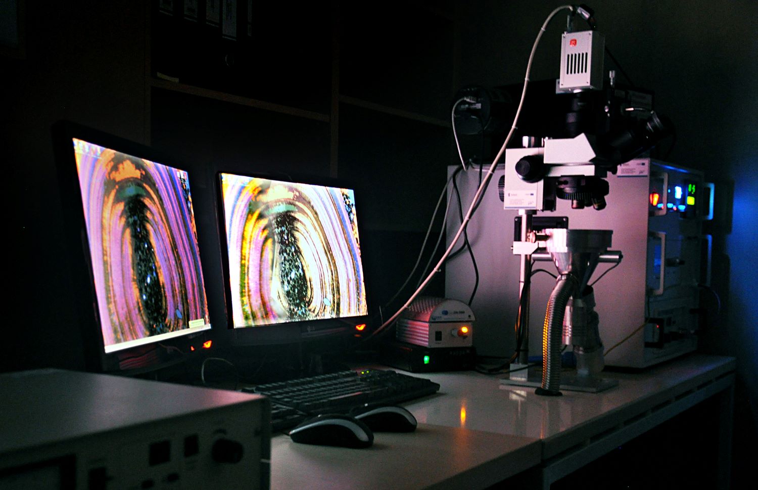Dwa monitory komputerowe z wyświetlonymi kolorowymi okręgami, z boku wyświetlacz i większa aparatura