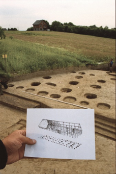 Widok pola z niewielkimi dziurami w ziemi, a na pierwszym planie kartka z narysowanym dachem budynku