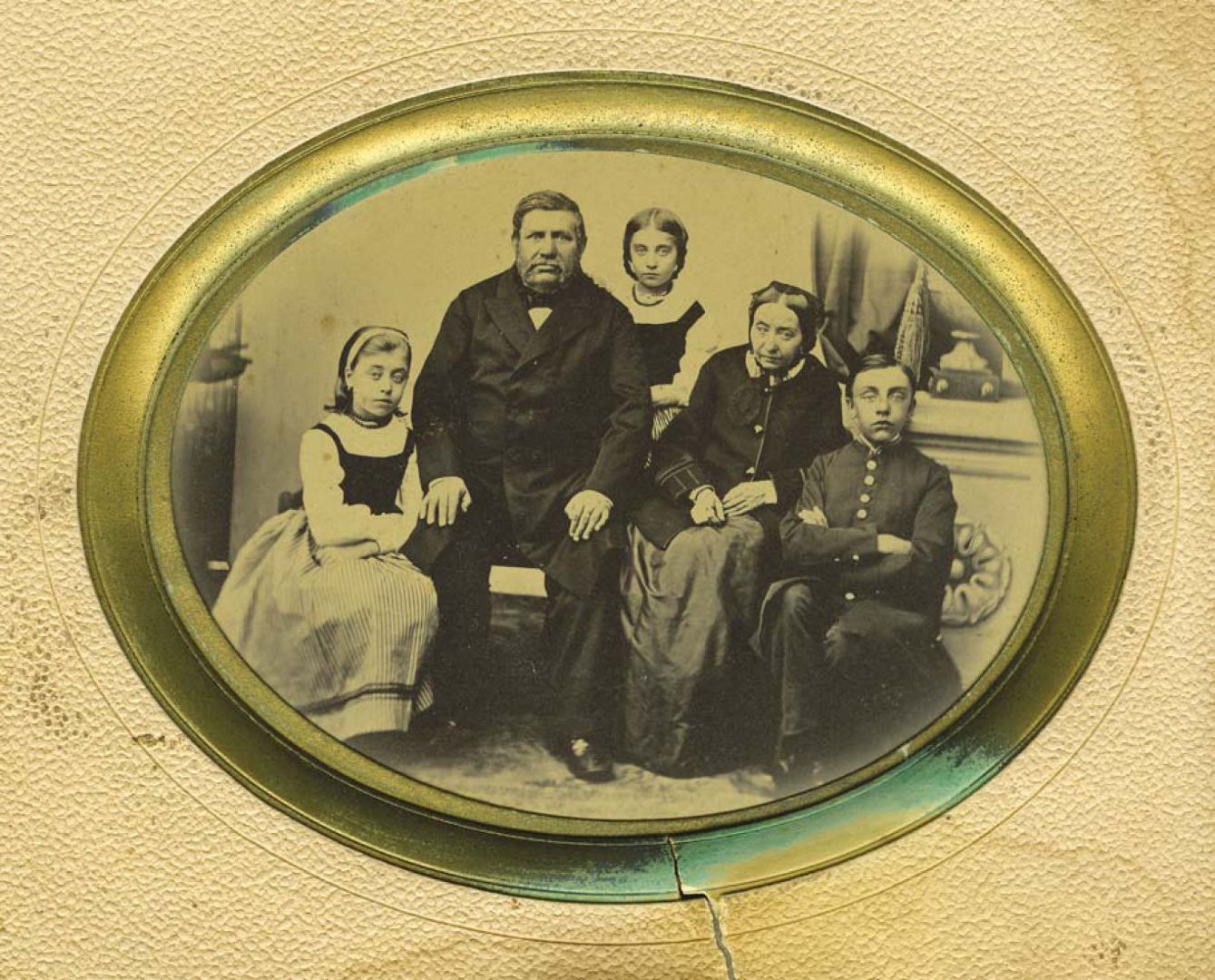 Owalna, czarno-biała fotografia, na której siedzi mężczyzna i kobieta oraz troje dzieci