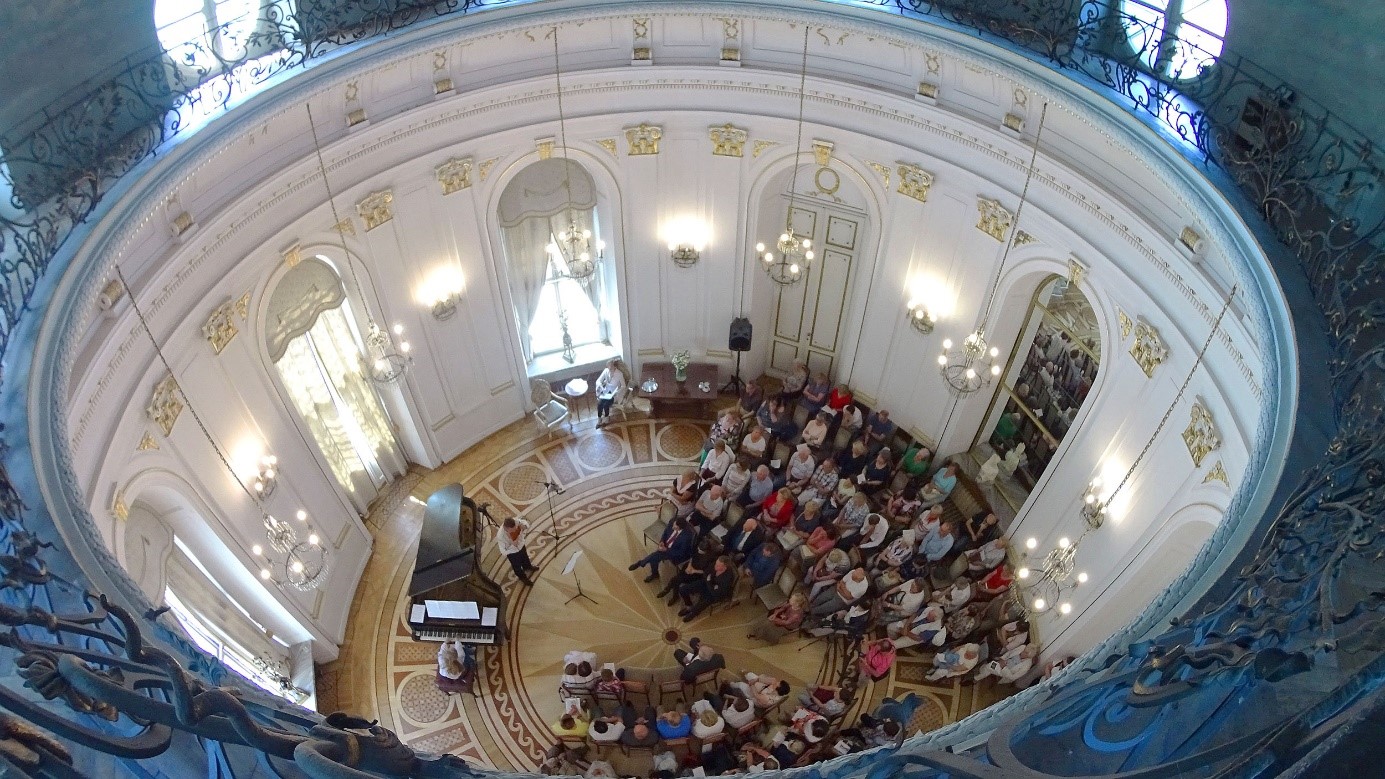 Okrągła sala pełna słuchaczy koncertu fortepianowego widziana z góry