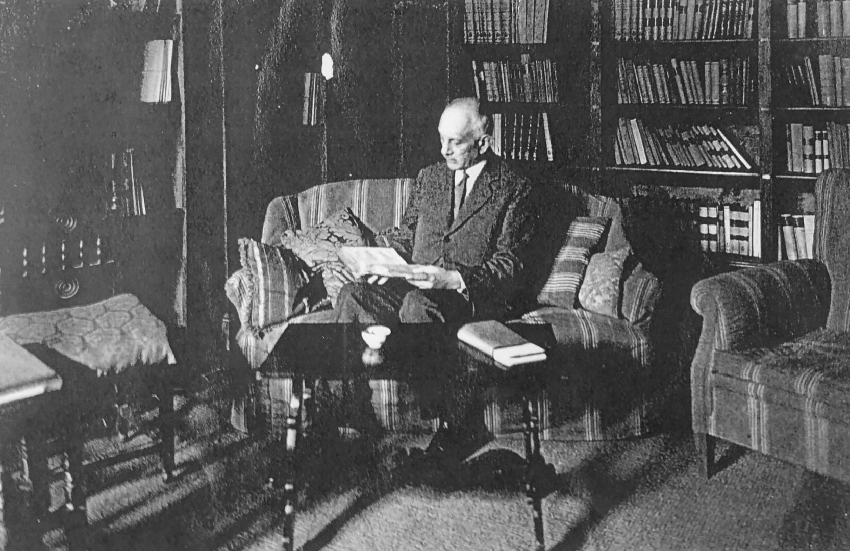 Czarno-biała fotografia, mężczyzna siedzi na kanapie i przegląda książkę