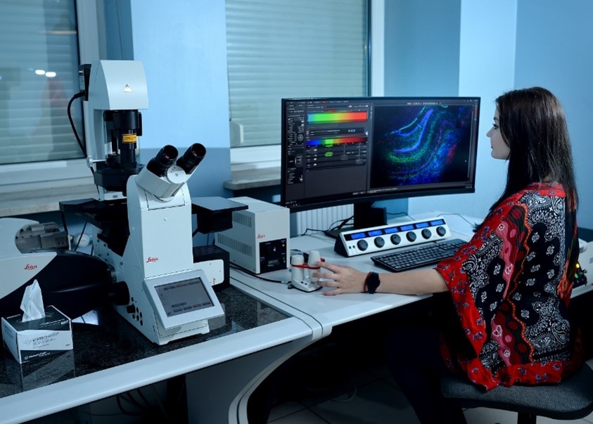 Młoda badaczka obserwuje preparaty komórkowe pod mikroskopem